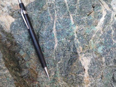 Altered diorite with stockwork, disseminated pyrite and malachite — pencil for scale (September 2026 release)